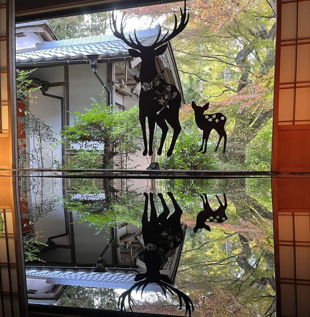 長寿寺の室内から見る紅葉と鹿の切り絵の映り込み